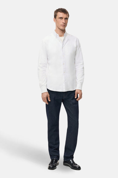 Chemise blanche à manches longues de MANGO, portée avec un jean bleu foncé et des mocassins noirs.