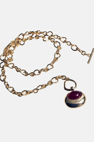Collier court doré de MANGO, avec une chaîne à maillons et un pendentif rond orné d'une pierre rouge.
