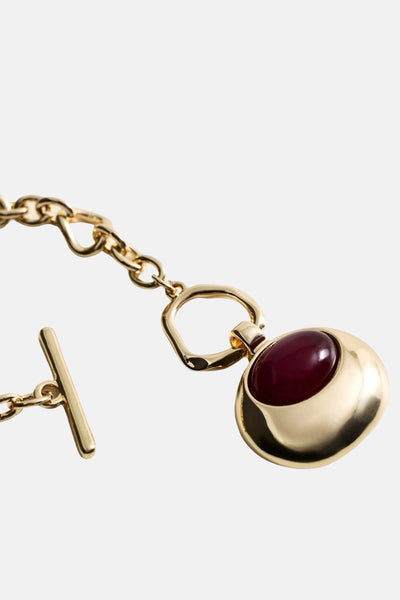 Collier court doré de MANGO, avec un pendentif rond et pierre rouge, fermoir en T.
