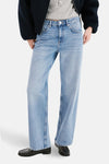 Jean droit en denim bleu clair de MANGO, porté avec un t-shirt gris, une veste bleu marine et des mocassins noirs.
