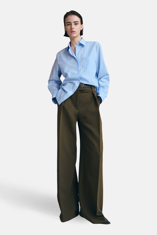 Chemisier bleu rayé à manches longues de MANGO, porté avec un pantalon taille haute et une ceinture noire.