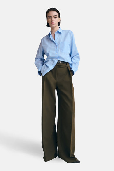 Chemisier bleu rayé à manches longues de MANGO, porté avec un pantalon taille haute et une ceinture noire.