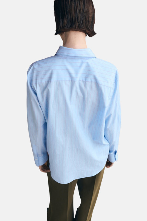 Chemisier bleu à rayures fines de MANGO, vue de dos, porté avec un pantalon kaki.