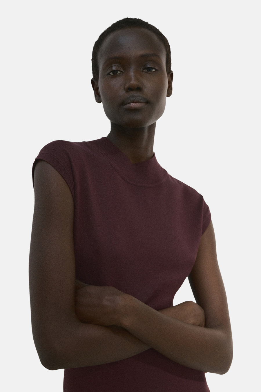 Robe à manches courtes brune de MANGO, portée par une femme aux bras croisés.