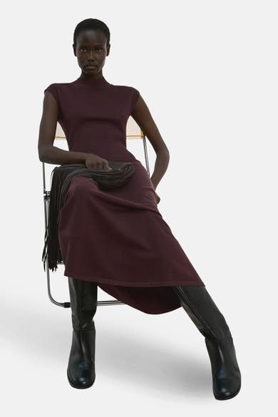 Robe à manches courtes marron de MANGO, portée avec des bottes en cuir noir et une pochette à franges.