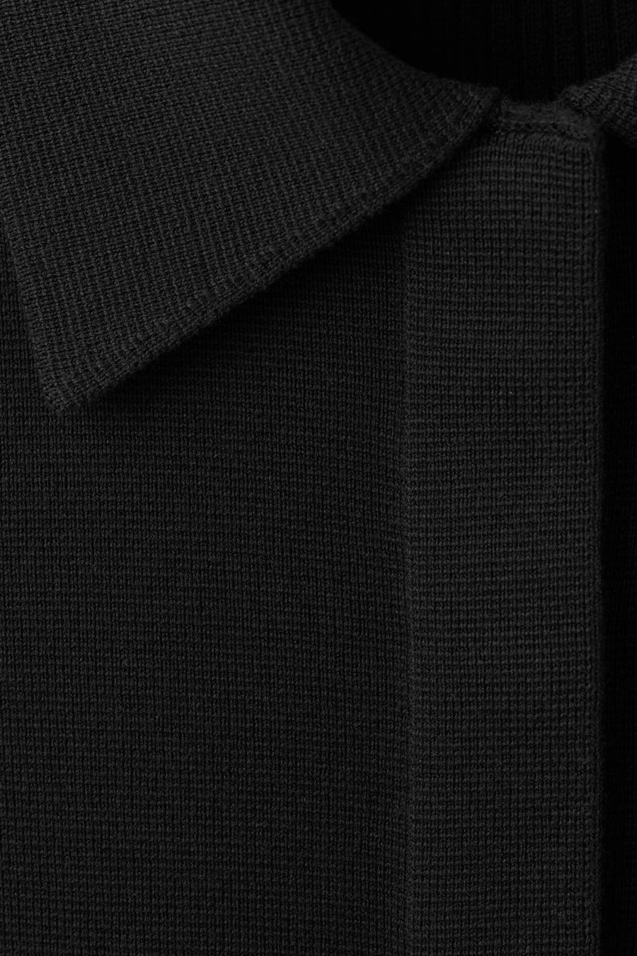 Gilet noir de MANGO, en maille côtelée avec col classique et patte de boutonnage.