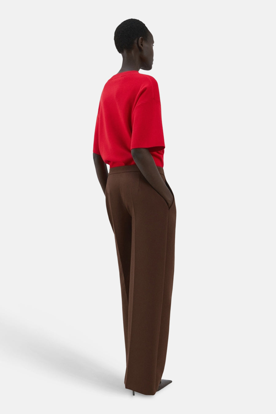 Pull col rond rouge de MANGO, porté avec un pantalon marron ample à jambes larges.