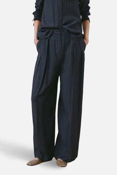 Blauwe gestreepte broek van MANGO, losse pasvorm en wijde pijpen, met zakken, van achteren getoond.