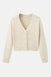 Cardigan écru de MANGO, avec une fermeture à nouettes décoratives sur le devant.
