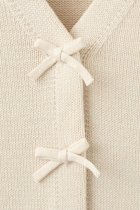 Cardigan écru de MANGO avec une texture tricotée et des liens décoratifs.