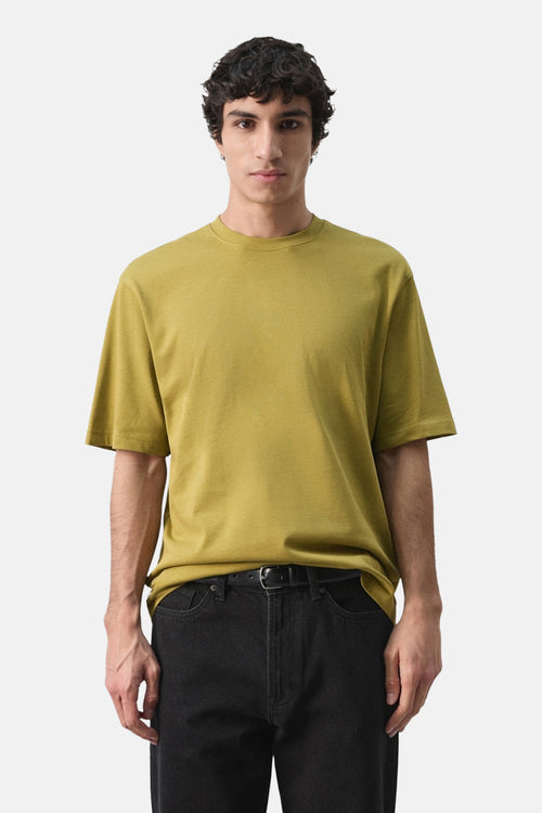 T-shirt à manches courtes vert de MANGO, porté avec un pantalon noir et une ceinture.
