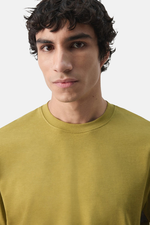 T-shirt à manches courtes vert de MANGO, uni, porté par un homme aux cheveux bouclés.