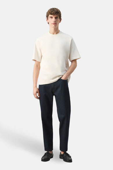 Ecru T-shirt met korte mouwen van MANGO, gedragen met een donkerblauwe broek en zwarte schoenen.
