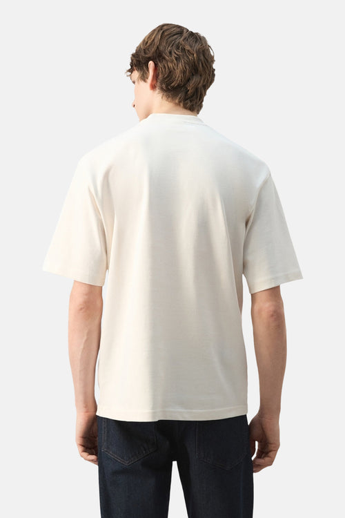T-shirt à manches courtes écru de MANGO, vu de dos, porté avec un jean foncé.