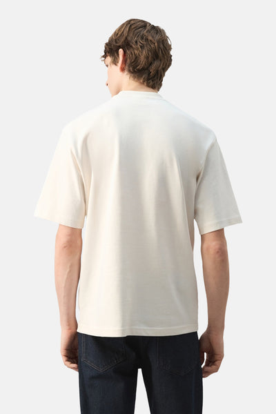 T-shirt à manches courtes écru de MANGO, vu de dos, porté avec un jean foncé.