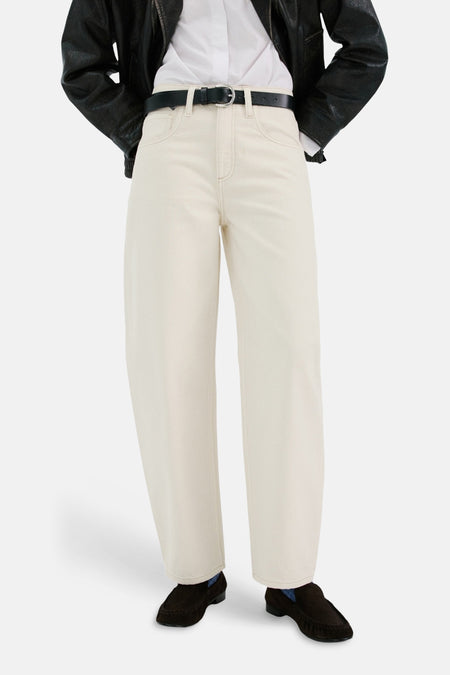 Jean en denim blanc de MANGO, porté avec une ceinture noire et des mocassins en daim marron.
