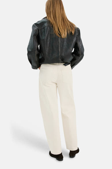 Jean en denim blanc de MANGO, porté avec une veste en cuir noir et des chaussures plates foncées.