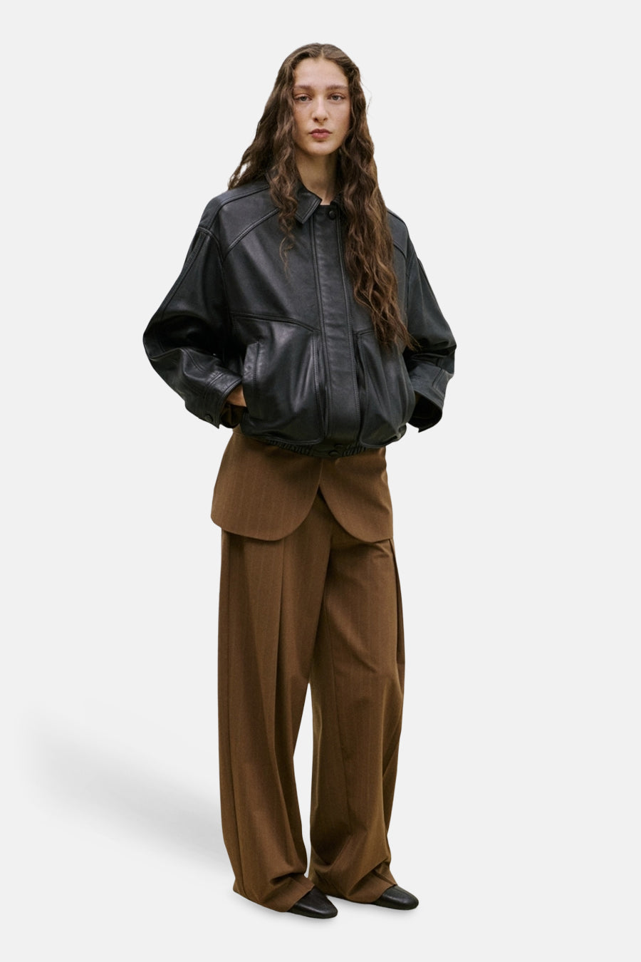 Bruine kostuumbroek van MANGO, wijdvallend met fijne verticale strepen, gedragen met een bijpassende blazer en een lichte sjaal geknoopt.