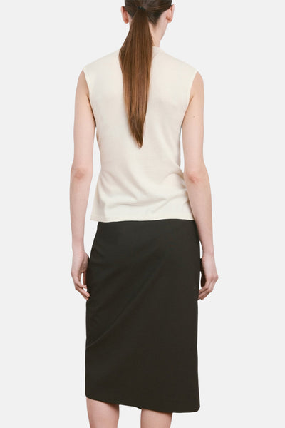 Top beige sans manches de MANGO, porté avec une jupe noire taille haute.