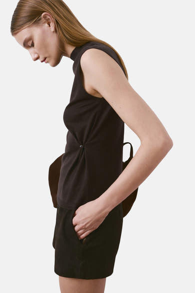 Bruin mouwloos topje van MANGO, gedragen met een zwarte korte broek en hoge laarzen.