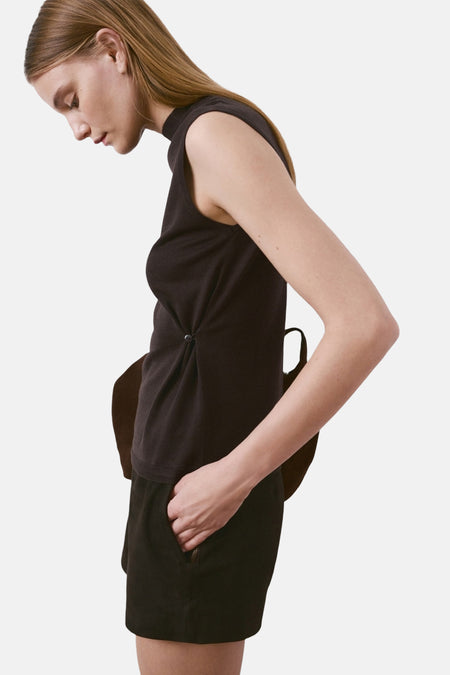 Bruin mouwloos topje van MANGO, gedragen met een zwarte korte broek en hoge laarzen.
