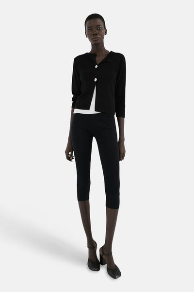 Zwart gilet van MANGO, gedragen over een wit T-shirt met een korte zwarte broek en zwarte hakken.