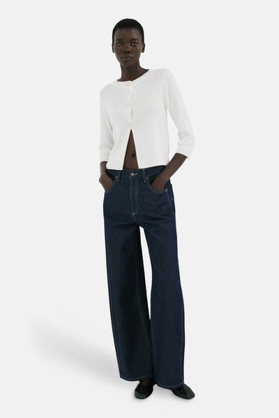 Wit vest van MANGO, open gedragen met een wijde donkerblauwe jeans en zwarte schoenen.