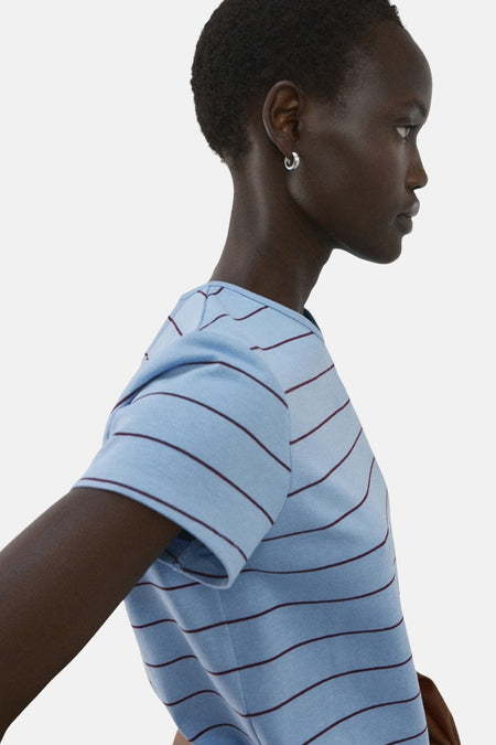 T-shirt bleu à rayures bordeaux de MANGO, porté par un mannequin en vue de côté avec des boucles d'oreilles argentées.
