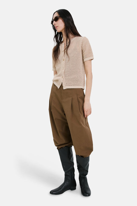 Beige gebreid vest van MANGO, gedragen met een wijde bruine broek en hoge zwarte laarzen.