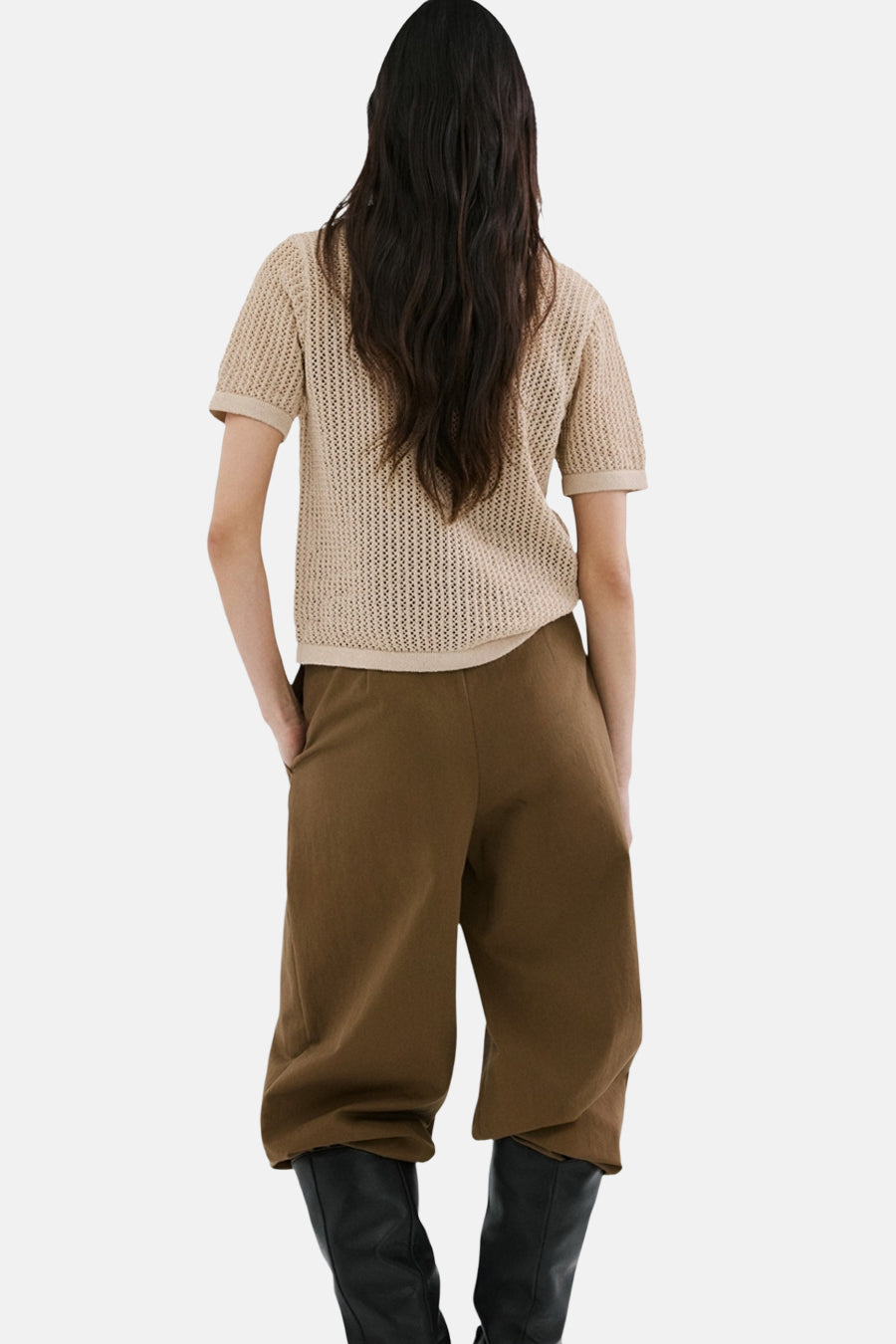 Gilet brun de MANGO, porté avec un pantalon marron ample et des bottes noires hautes, vue de dos.

