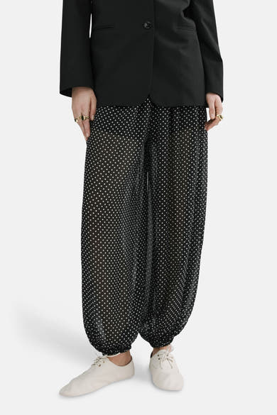 Zwarte broek van MANGO met witte stippen, met een zwart jasje en een witte sjaal.