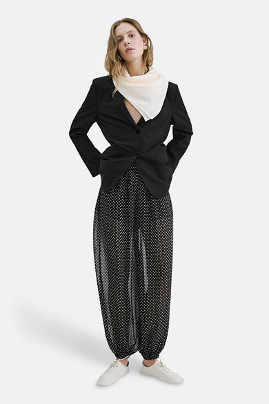 Zwarte broek met witte stippen van MANGO, doorschijnende haremstijl gedragen met een blazer en een ivoorkleurige sjaal.