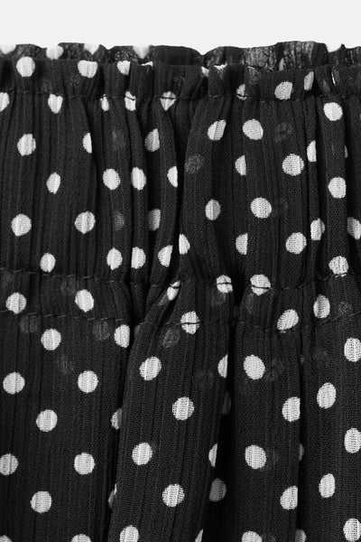 Pantalon noir froncé à pois blancs de MANGO, avec un tissu texturé et une coupe ample.