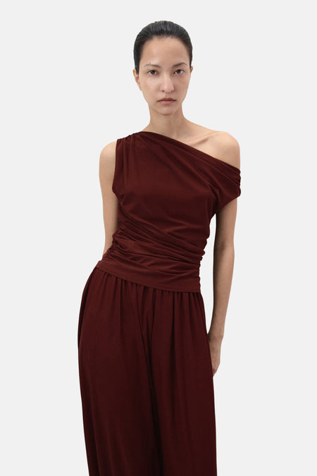 Top sans manches brun de MANGO, drapé asymétrique sur une épaule, porté avec un pantalon assorti.