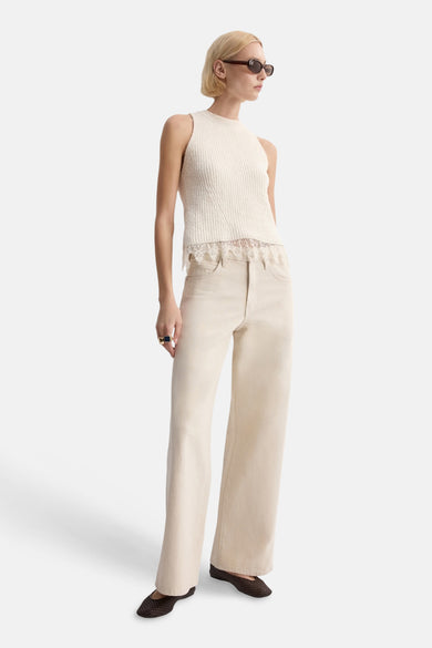 Top sans manches écru de MANGO, avec bordure en dentelle et texture côtelée, porté avec un jean ample et des chaussures plates.
