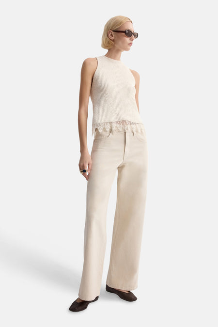 Top sans manches écru de MANGO, avec bordure en dentelle et texture côtelée, porté avec un jean ample et des chaussures plates.