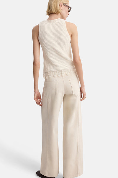 Top écru sans manches de MANGO, orné de dentelle à la base, porté avec un pantalon beige taille haute.
