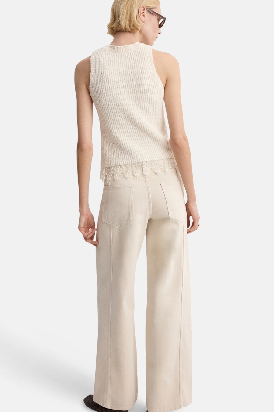 Top écru sans manches de MANGO, orné de dentelle à la base, porté avec un pantalon beige taille haute.