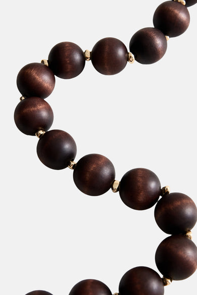 Korte bruine ketting van MANGO, met ronde houten kralen en gouden details tussen elke kraal.