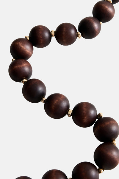 Korte bruine ketting van MANGO, met ronde houten kralen en gouden details tussen elke kraal.