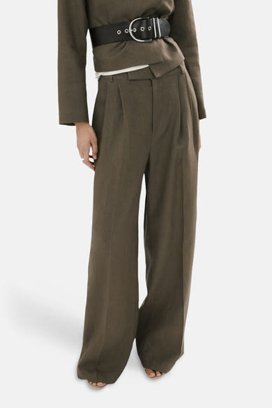 Kaki broek van MANGO, wijde pasvorm, met paspelzakken achter, en gedragen met een kort bruin jasje.