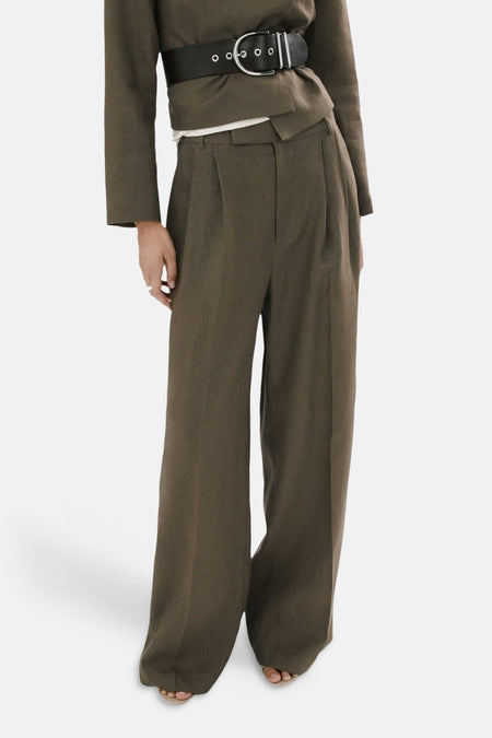 Pantalon kaki de MANGO, ample avec des plis et une ceinture noire en cuir visible.
