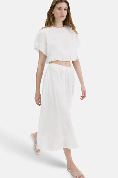 Jupe longue beige de MANGO, avec des motifs floraux brodés et une coupe fluide.