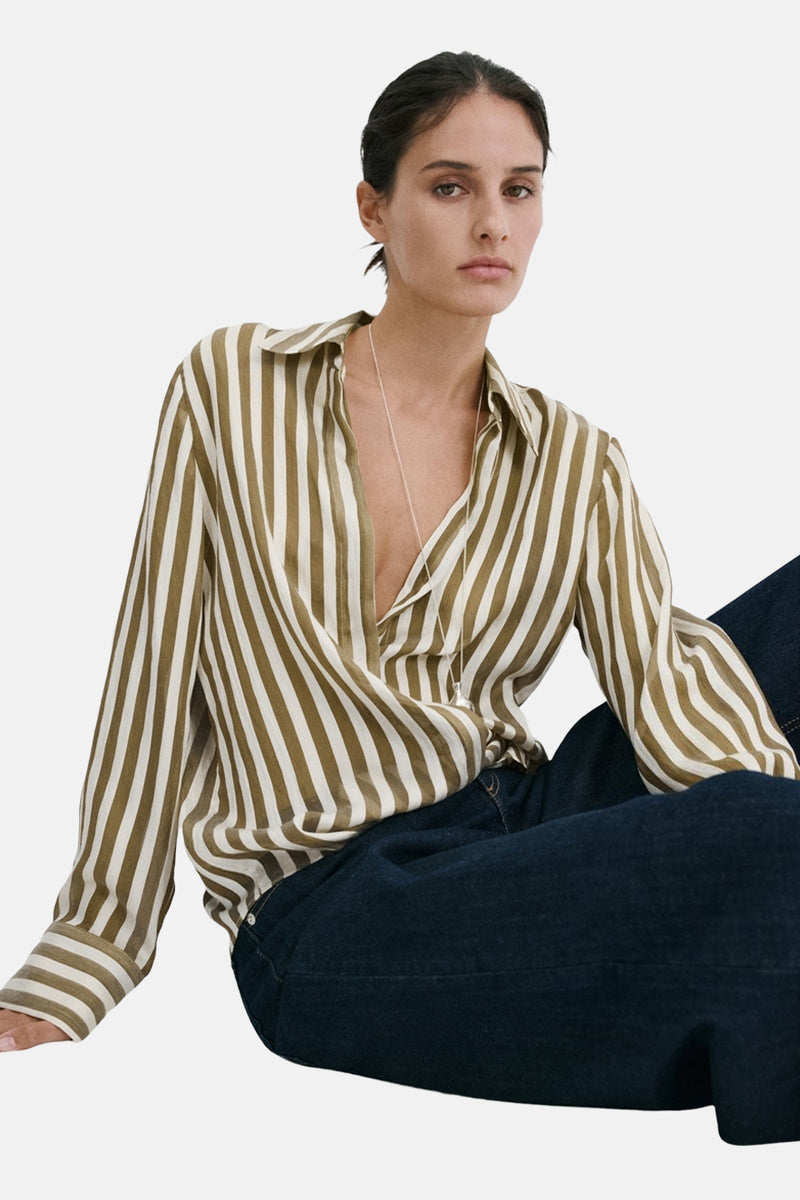 Chemise à manches longues rayée vert olive et crème de MANGO, ouverte sur le décolleté, portée avec un jean foncé.