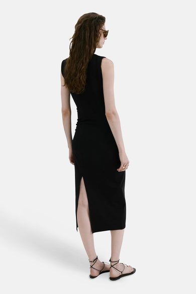 Robe noire de MANGO, coupe midi, fendue dans le dos, portée avec des sandales à lacets noires.
