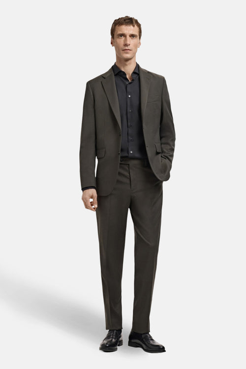 Chemise noire à manches longues de MANGO, portée avec un costume gris foncé et des chaussures noires.