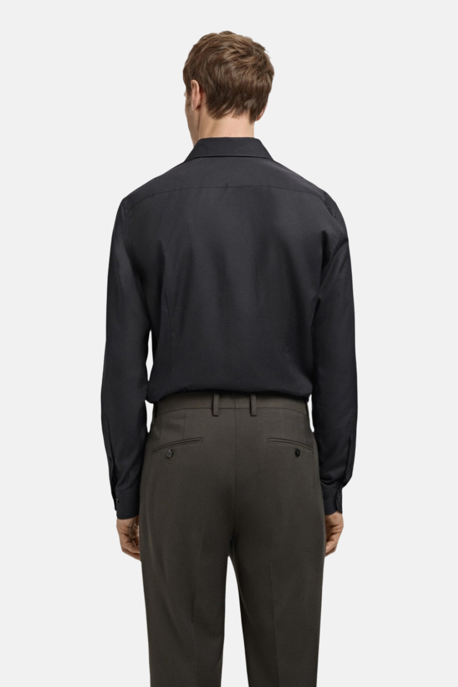 Chemise noire à manches longues de MANGO, vue de dos, portée avec un pantalon gris anthracite.