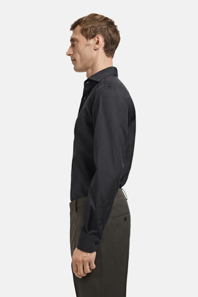 Zwart overhemd met lange mouwen van MANGO, zijwaartse weergave van een man die een antracietkleurige broek draagt.