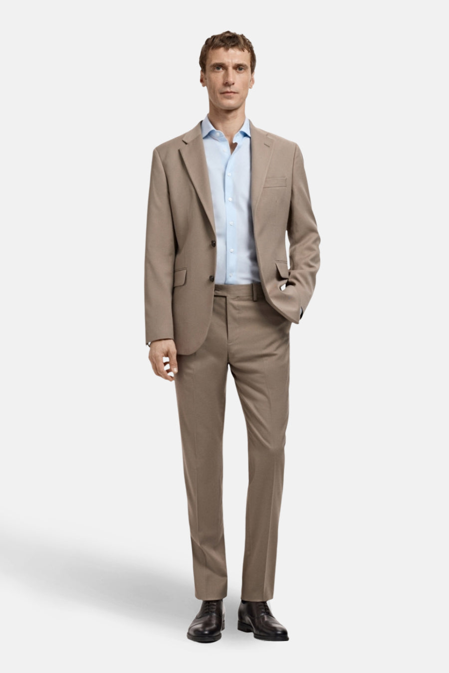 Chemise à manches longues bleue de MANGO, portée avec un costume marron, sur fond blanc.
