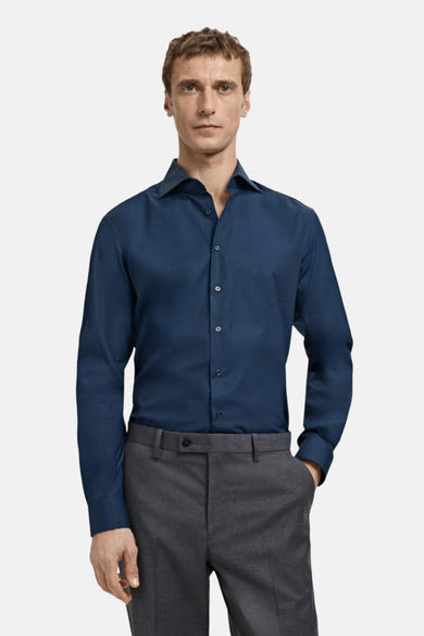 Chemise à manches longues bleue de MANGO, portée avec un pantalon gris anthracite.